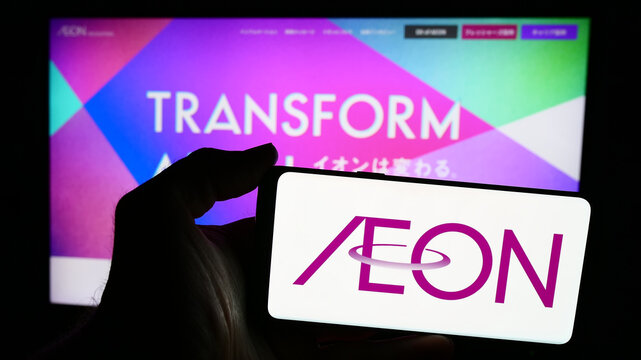 Stuttgart, Germany - 07-29-2024: Person holding smartphone with logo of Japanese retail holding company Aeon Co. Ltd. in front of website. Focus on phone display.