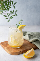Mojito cocktail with fresh lemon, mint and ice. Refreshing citrus lemonade drink on a wooden board on a light background with leaf and napkin.