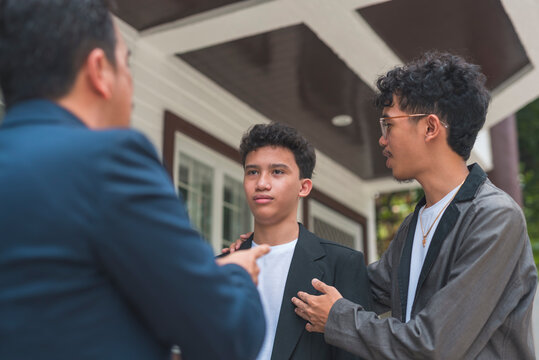 A father trying to teach his son a lesson, criticizing his grades, while his brother tries to encourage him to do better. Showing tough love. Outdoor scene.