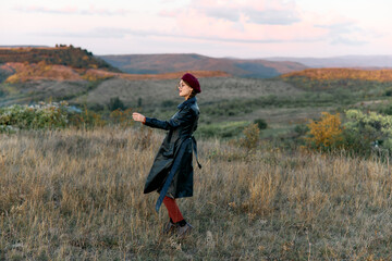 Mysterious woman in black coat and red hat standing alone in a vast open field