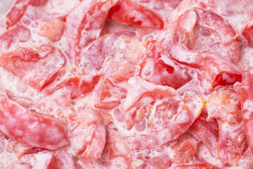 Sliced tomatoes prepared for a salad. Fresh tomato salad with cream as a side dish for lunch or dinner. Vibrant and healthy addition to any meal. Vegetables texture. Tomato background.
