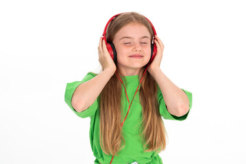 Happy girl in green summer outfit dancing enjoying music in red headphones on white background