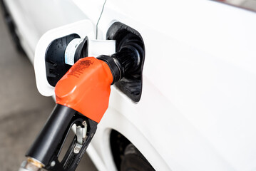 Close-up gas pump nozzle lever lock activated inserts into capless fuel filler refueling for modern SUV minivan car slide door at gas station in San Antonio, Texas, oil and gas, transportation