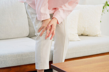 膝が痛いシニア女性　リビングルーム　顔無し