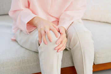 膝が痛いシニア女性　リビングルーム　顔無し
