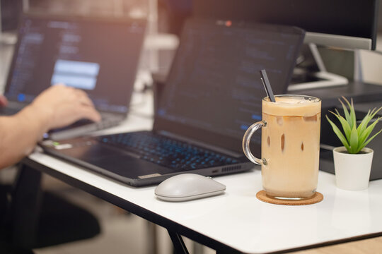 Close up glass of ice coffee with laptop on table at office.Work space concept.