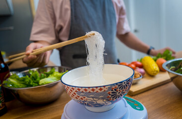 Chef at the kitchen preparing spicy glass noodle salad
