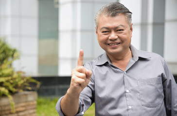 Smart Confident happy smiling middle aged old asian man pointing up 1 finger, hand gesture for one point, number 1 or first place