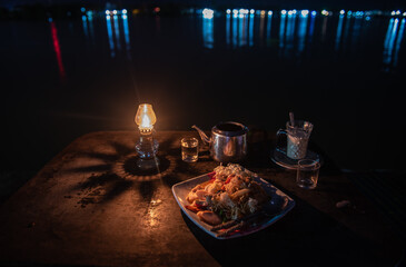 Light an oil lamp on a coffee table by the water in the evening.