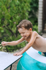 Little smiling boy, happy hungry child swims in pool in summer, holds fruits berries grapes in hands. Photography, portrait.