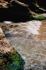 Sea. Water splashes. Shore. Waves. Sea foam. Rock in the middle of the sea. Sand. Seaweed. Summer vacation. Resort on the seashore. Waves. Stones with seaweed.