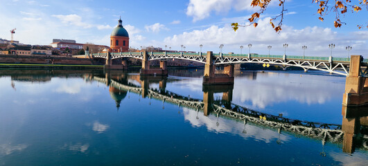 Pont Neuf Over the Garonne River with Reflections on the Water and Hôtel-Dieu Saint-Jacques in the Background Under a Clear Blue Sky, Toulouse