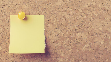 A bright yellow sticky note pinned on a corkboard, ready for reminders or quick notes, against a textured, earthy background.
