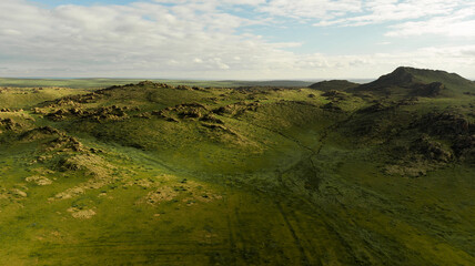 Aerial view of the lush green landscape and rocky formations in Algui Ulaan Tsav, Gobi, Mongolia under a partly cloudy sky.