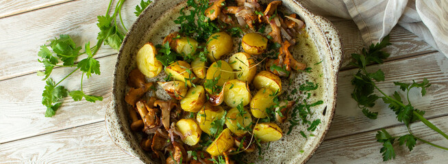 baked new potatoes with garlic, rosemary and chanterelles on a light table, top view
