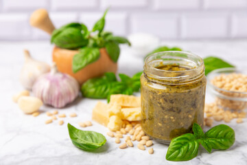 Pesto. Italian basil pesto sauce on a textured wooden background. Ingredient for pesto sauce: fresh basil, pine nuts, Parmesan cheese and olive oil. Space for text.Copy space.