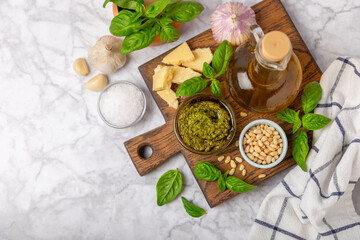 Pesto. Italian basil pesto sauce on a textured wooden background. Ingredient for pesto sauce: fresh basil, pine nuts, Parmesan cheese and olive oil. Space for text.Copy space.