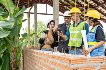 Construction team and civil engineers work together to check the humidity levels of concrete walls in a house under construction.