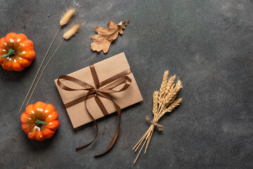 Brown envelope tied with a ribbon with autumn decorations on a dark background. Invitation card, gift certificate or present. Top view, lay flat.