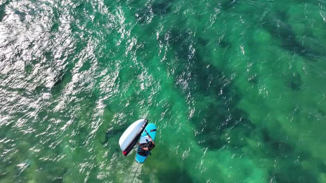 Aerial drone tracking video of fit athlete practise hydro foil wing surfing in tropical exotic island bay with crystal clear emerald sea