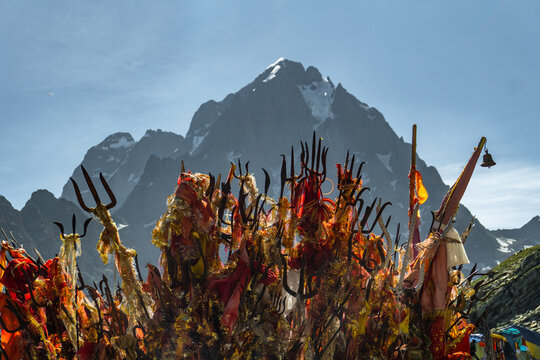 Religious red cloths (chunri) and tridents (trishul), symbols of Lord Shiva, against Kailash Parvat during the Mani Mahesh Kailash Yatra, a Hindu and Buddhist pilgrimage.
