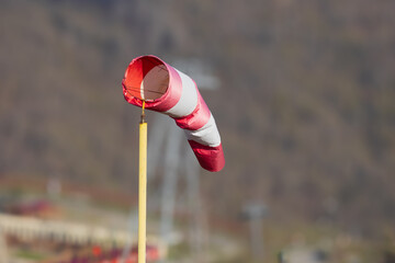 Dangling red and white windsock in calm weather in the ski resort on blurred background