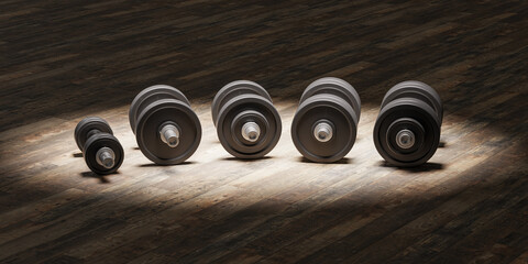 Several dumbbells in a row with  incremental weights on a hardwood floor under a spotlight.