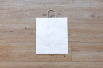 White paper bag on beige background with copy space