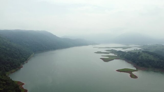 Aerial view of umiam lake serene blue water with misty mountains aerial image is taken at umiam lake shillong meghalaya india. it is showing the breathtaking beauty of nature.