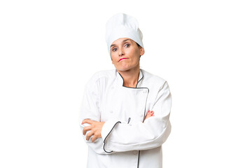 Middle-aged chef woman over isolated background making doubts gesture while lifting the shoulders