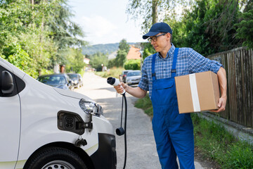 Delivery man in uniform holds electric vehicle charging plug next to electric van