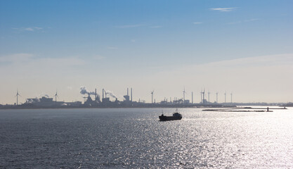 Obraz premium Ship in the North sea with steel factory in the background in IJmuiden, Netherlands