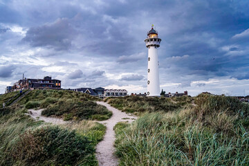 Netherlands. Egmond aan Zee.  Van Speijk Lighthouse with blue sky and clouds and burning light