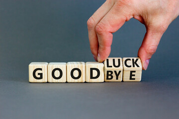 Good luck or goodbye symbol. Concept words Good luck or Goodbye on beautiful wooden blocks. Beautiful grey background. Businessman hand. Business, motivational good luck concept. Copy space.