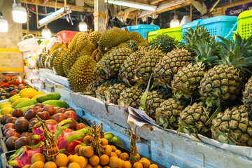 Variety of fresh tropical fruits displayed at a market stall. Colorful display of fresh durians,...
