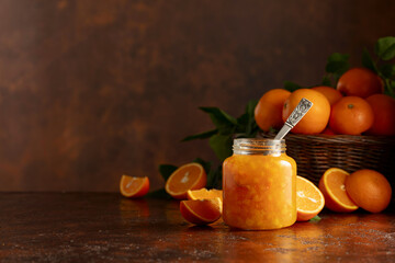 Orange jam and fresh fruits on a brown vintage table.
