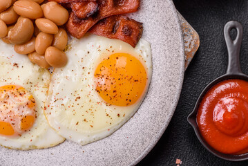 English breakfast with fried eggs, bacon, beans, tomatoes, spices and herbs