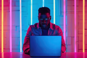 male IT engineer focused on laptop amidst vibrant neon lighting