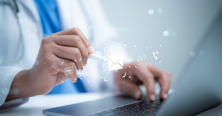 A medical worker using a laptop and touching contact us button email, address, live chat, internet...