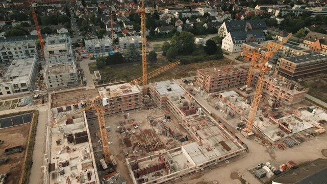 Aerial view of a large construction site. All logos removed. The perspective shifts and the cranes slowly rise into the beautiful blue sky with white clouds 