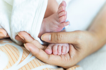 A mother's hands lovingly holding her newborn baby's feet. Concept Mother's day, Baby foot.