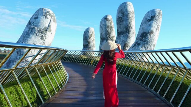 4k slow motion,Asian woman wearing red.Vietnamese culture with traditional conical hat withon the Golden han Bridge, Da Nang City, Vietnam.