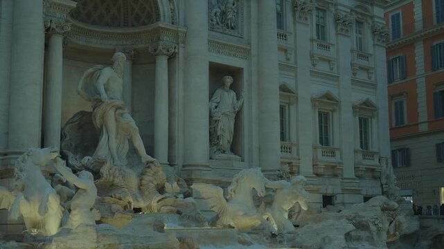 Trevi Fountain, A large white building with statues of people and animals on it. The statues are of a man and a woman, and a horse. The building is very old and has a lot of detail