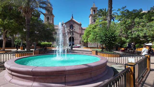 A vibrant view of the fountain at Plaza de la Constituci&oacute;n, with the backdrop of the historic Parroquia Arciprestal de la Inmaculada Concepci&oacute;n in Torrevieja.