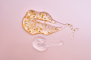 Fototapeta premium Texture of face serum and serum with 24k gold on a pink background.