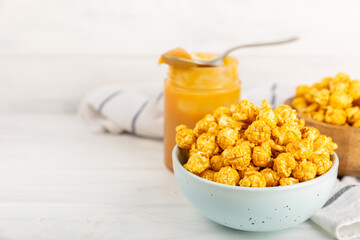 Sweet caramel popcorn in a bowl on a wooden background. Salted caramel popcorn. Caramel sauce. Close up. Topping. Place for text. Copy space