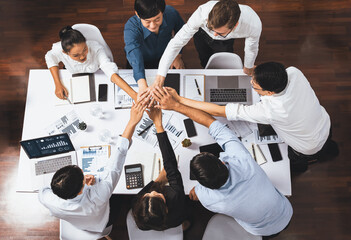 Top view diverse office worker join hand together in office room symbolize business synergy and strong productive teamwork in workplace. Cooperation and unity between business employee. Prudent