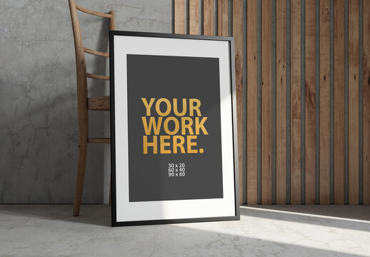 Vertical Poster with Black Frame Mockup standing on the floor next to wooden stool