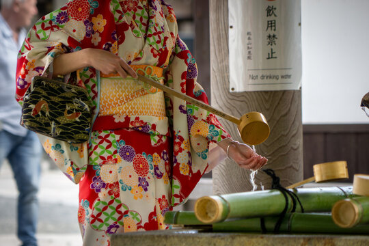 Japanese woman in a colorful kimono washing her hands in a temple