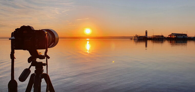 Photographer is taking photo of famous lighthouse on the Podo beach in Neusiedler See during sunset. Tourist attraction of Podersdorf am See. Burgenland, Austria.